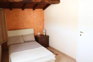 a bedroom with a white bed and a night stand at Casa vacanze Elena in Rometta