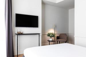 バルセロナにあるMaldà Singular Hotelの白い部屋(ベッド1台、壁にテレビ付)