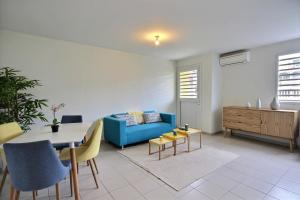 a living room with a blue couch and a table at Appartement Pomme Cannelle 1 chambre, moderne, au coeur de Fort de France in Fort-de-France