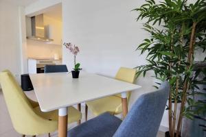 a dining room with a white table and chairs at Appartement Pomme Cannelle 1 chambre, moderne, au coeur de Fort de France in Fort-de-France