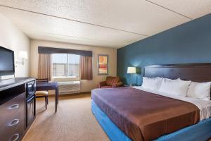 a hotel room with a bed and a flat screen tv at AmericInn by Wyndham Monmouth in Monmouth