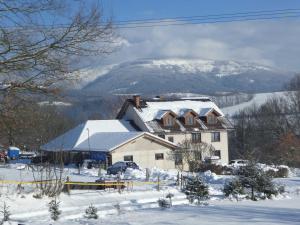 een huis bedekt met sneeuw met een berg op de achtergrond bij Ubytování Farma U sv. Jakuba in Dolní Lánov