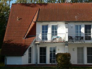 a white house with a red roof and a balcony at Ferienwohnung Ankerplatz_VOLB in Ostseebad Karlshagen