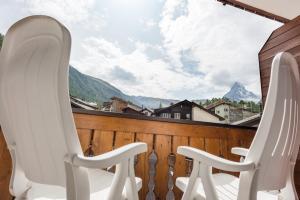 two white chairs on a balcony with a view of mountains at Hotel Rhodania in Zermatt