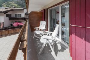 Dos sillas blancas sentadas en el balcón de una casa en Hotel Rhodania en Zermatt