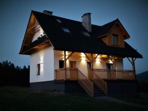 a large white house with a deck at night at Chata Wielki Potok in Istebna