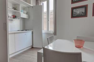 a white kitchen with a white table and chairs at La Casa Sui Fori in Rome