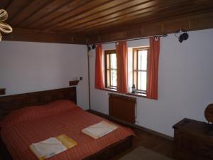 a bedroom with a bed and two windows at Guest House Dimcho Kehaia's Cafe in Zheravna