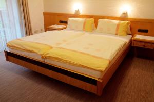 a bedroom with a large bed with yellow sheets and pillows at Pension Epple in Oberjoch