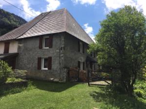 une vieille maison en pierre avec un arbre dans la cour dans l'établissement Charmante maison familiale, à Saint-Pierre-de-Chartreuse