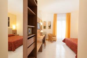 Cette chambre comprend deux lits et un bureau. dans l'établissement Albergo Vittoria, à Salsomaggiore Terme