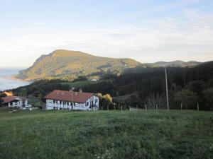 a house in a field with a hill in the background at EA playa montaña45'GUGGEMHEIN in Ea