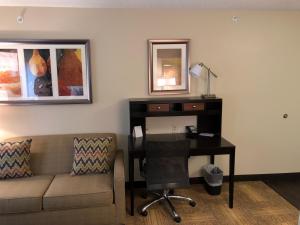 ein Wohnzimmer mit einem Sofa und einem Schreibtisch mit einem Computer in der Unterkunft Staybridge Suites Grand Rapids-Kentwood, an IHG Hotel in Grand Rapids