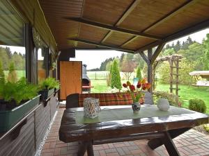 eine Terrasse mit einem Holztisch mit Blumen darauf in der Unterkunft Ferienbungalow Poppengrün in Poppengrün