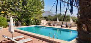 a swimming pool with chairs and umbrellas next to it at Casa de Los Lirios in Muro de Alcoy