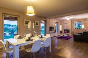 een eetkamer en een woonkamer met een witte tafel en stoelen bij Villa Danelon in Poreč