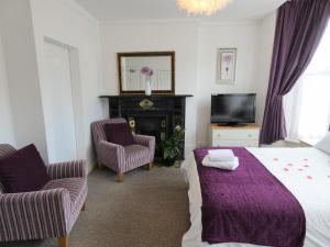 a bedroom with a bed and two chairs and a tv at Rialto Holiday Apartments in Bridlington
