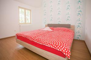 a bedroom with a bed with a red and white comforter at Holiday House Hacienda in Montižana +24 photos