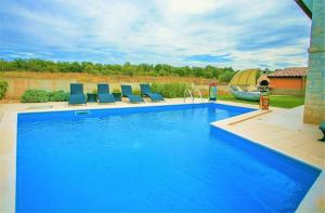 a swimming pool with blue chairs in a backyard at Holiday House Hacienda in Montižana