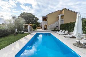 a pool in front of a house with chairs and an umbrella at Villa Ladonja with Private Pool and Sauna in Marasi