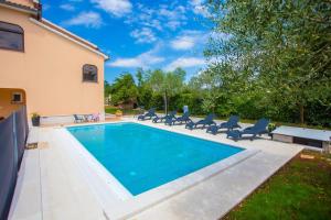 a swimming pool with lounge chairs next to a house at Three-Bedroom Apartment Mir with Private Infinity Pool in Vošteni