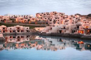 a group of houses on a hill next to a body of water at The Cove Rotana Resort - Ras Al Khaimah in Ras al Khaimah