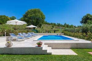 einen Pool mit Stühlen und einem Sonnenschirm in der Unterkunft Stone House Rita with Pool in Poreč