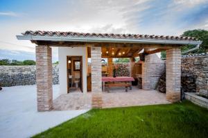 un patio con una pared de piedra y una pérgola de madera en Exclusive Villa Tomani with Private Pool en Krmed