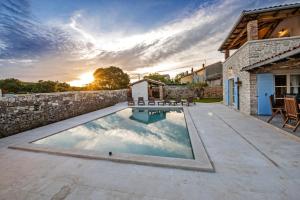 a swimming pool in a backyard with a stone wall at Exclusive Villa Tomani with Private Pool in Krmed