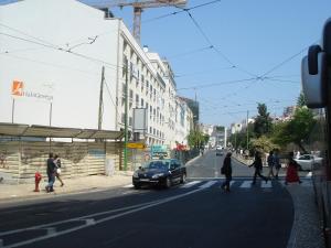 un grupo de personas cruzando una calle con un coche en Baixa GuestHouse, en Lisboa