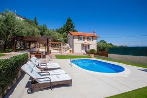 a pool with lounge chairs next to a house at Villa Olive with Pool and Sea View in Ičići