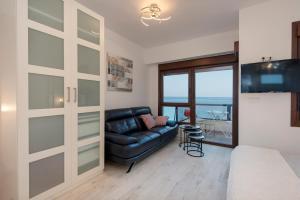 a living room with a black leather couch and a sliding glass door at ALOHA 804 in Benalmádena