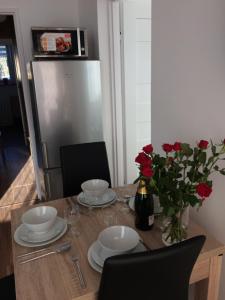 una mesa con platos y un jarrón de rosas. en Apartament Pod sanockim zamkiem en Sanok