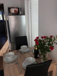 a table with plates and a vase of roses on it at Apartament Pod sanockim zamkiem in Sanok