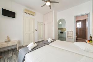 a white bedroom with a large bed with a ceiling fan at Apartments Tarsa in Drios