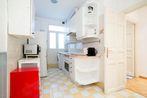 eine Küche mit weißen Schränken und einem roten Stuhl in der Unterkunft Chueca Just For You in Madrid