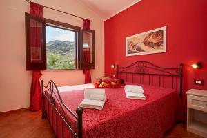 a red bedroom with a bed with red sheets and a window at Villa Ninetta in Scopello