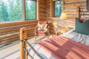 a bedroom with a bed and a chair in a log cabin at Huckleberry Hideaway in Big Sky