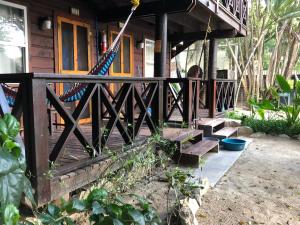un porche de una casa con valla y escaleras en Bananarama Dive & Beach Resort, en West Bay