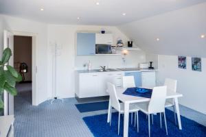 a kitchen with white cabinets and a table and chairs at Modrin Apartments in Kamnik