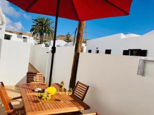 een houten tafel met een rode parasol op een patio bij Canaryislandshost l Lovely Lanzarote in Nazaret