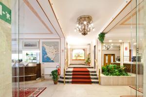 eine Lobby mit Treppen und einem Kronleuchter in der Unterkunft Hotel Terminus & Plaza in Pisa