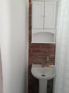a bathroom with a white sink and a cabinet at Central 390 Isla Negra in Isla Negra +34 photos