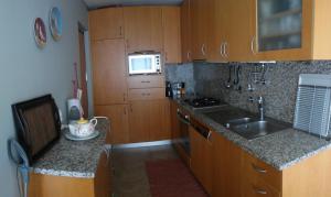 uma cozinha com armários de madeira, um lavatório e um micro-ondas em Perfect Sea View em Vila do Conde