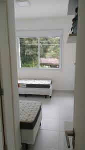 a room with two mattresses in front of a window at Pé na areia em Boiçucanga condominio Aquamarine - perto de Maresias e Camburi in Boicucanga +26 photos