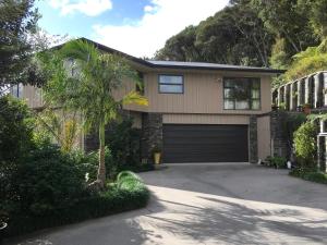 a house with a garage and a palm tree at Puka Heights in Pauanui