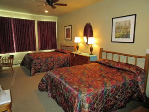 
a hotel room with two beds and two lamps at Soda Butte Lodge in Cooke City
