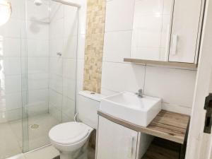 La salle de bains blanche est pourvue de toilettes et d'un lavabo. dans l'établissement Casa 3 quartos Bombinhas lado Mar ou AP de 2 quartos, à Bombinhas