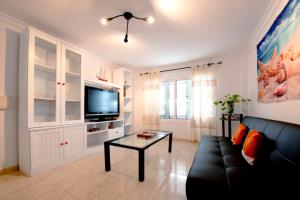 - un salon avec un canapé noir et une télévision dans l'établissement Apartamento "La casa de la Playa" con wifi y 3 dormitorios, à Arinaga