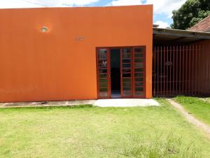 Pousada Vancele في بونيتو: مبنى برتقالي مع باب احمر في ساحة